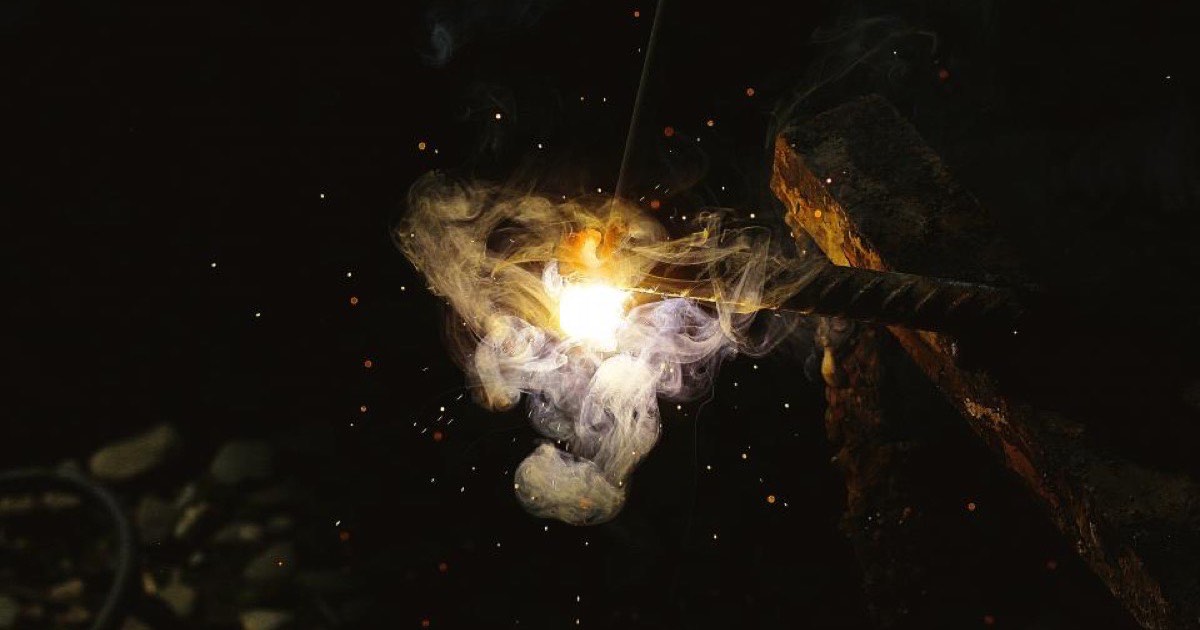 Pulsed fibre laser beam removing a coating from a metal surface